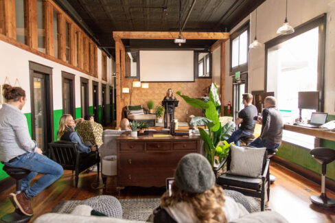 Shawna teaching a class at Nest:Space™ coworking from the stage on the main level, designed by Shawna Meyer Design™, Interior Design and Project Management